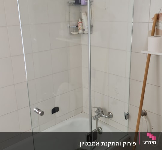 מקלחת עם אמבטיה, דלת זכוכית ומדף עם מוצרי טיפוח